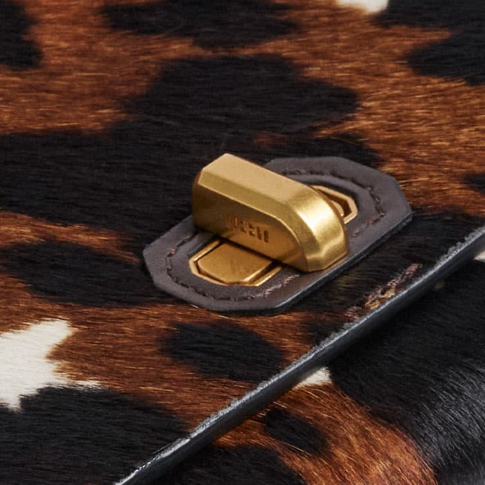 The twist-and-lock fastening is gold-plated and elevated with abstract bespoke block branding.