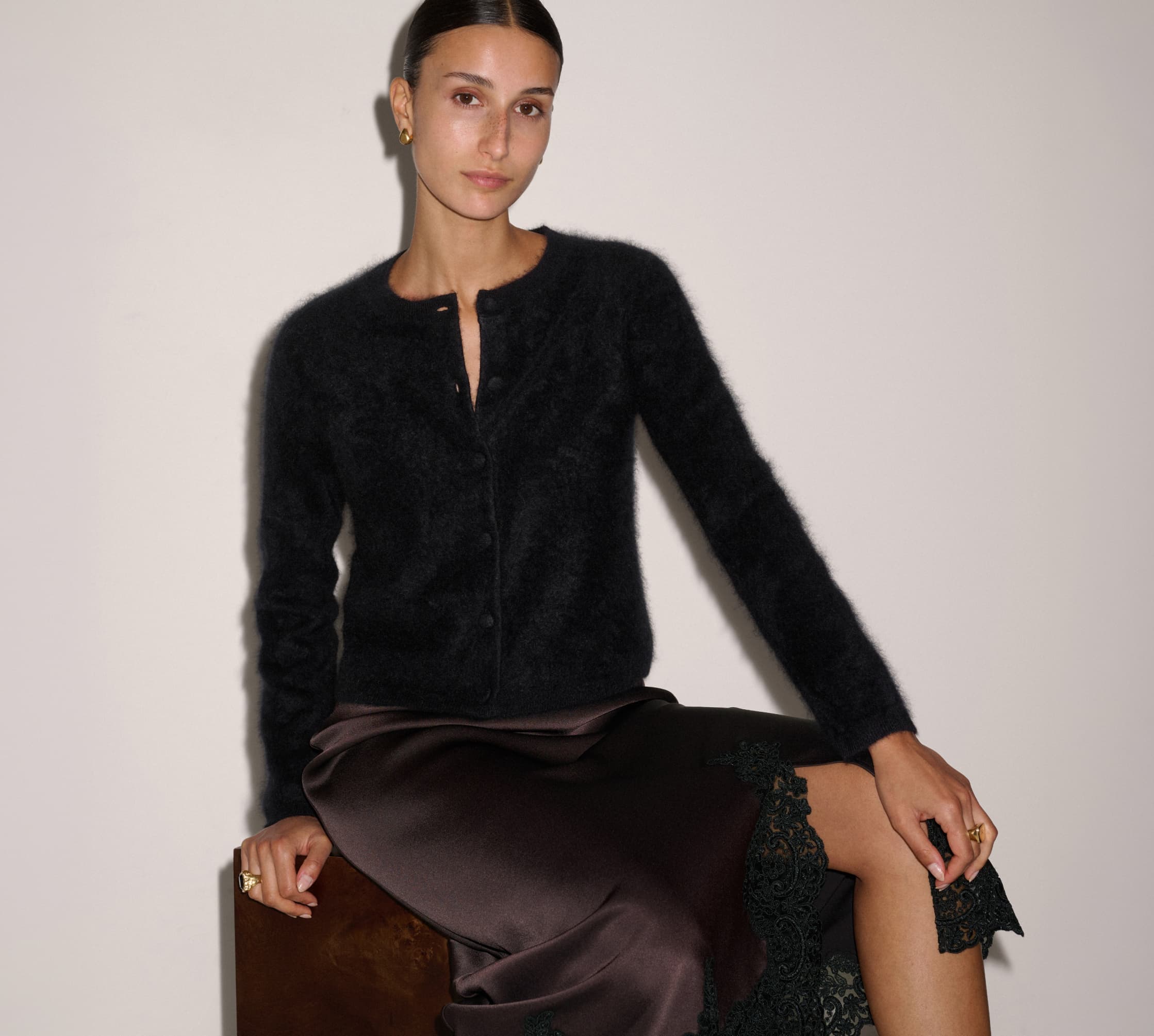 Model wearing a white shearling coat and grey cardigan.