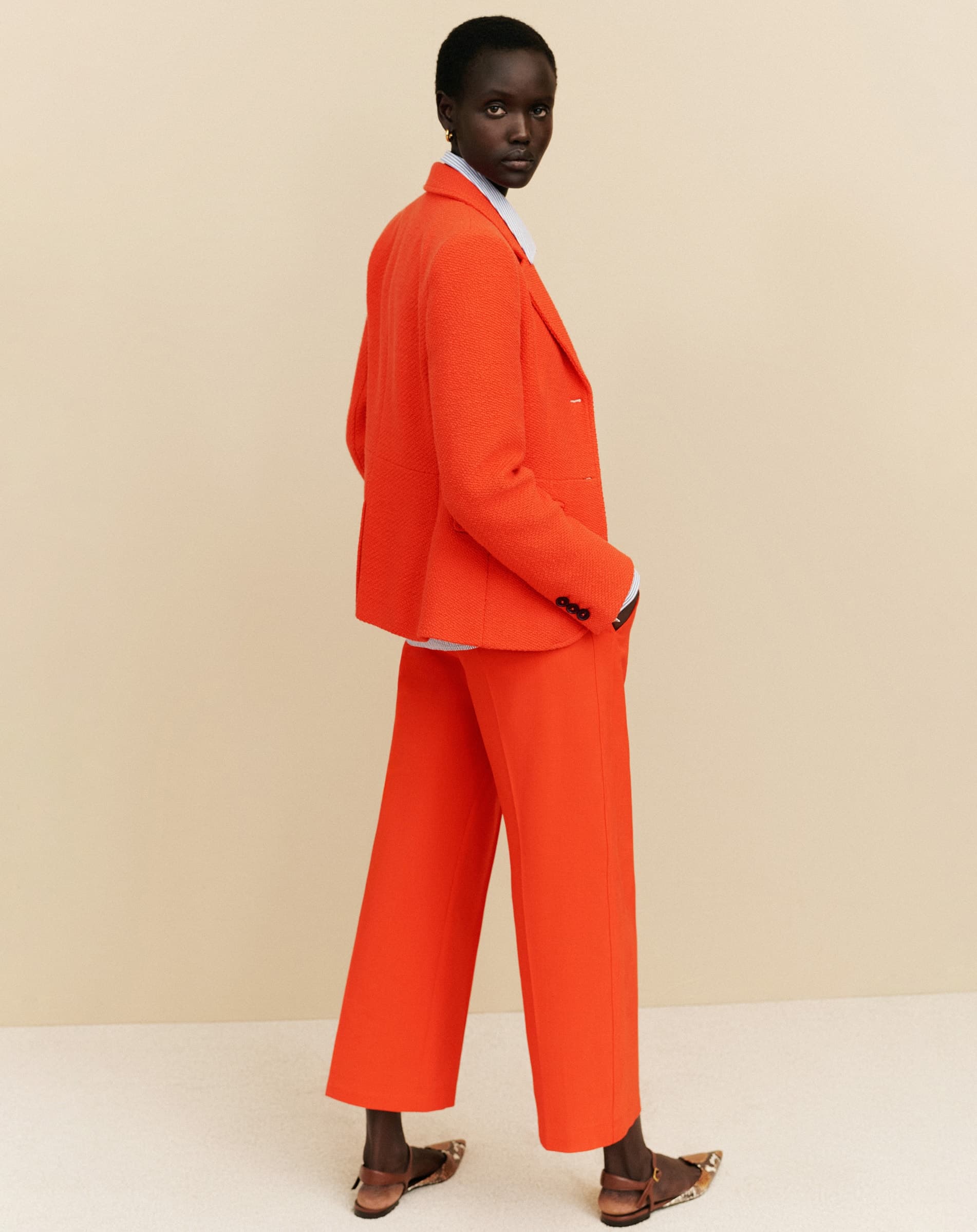 A woman with her back to the camera wearing a bright orange suit.