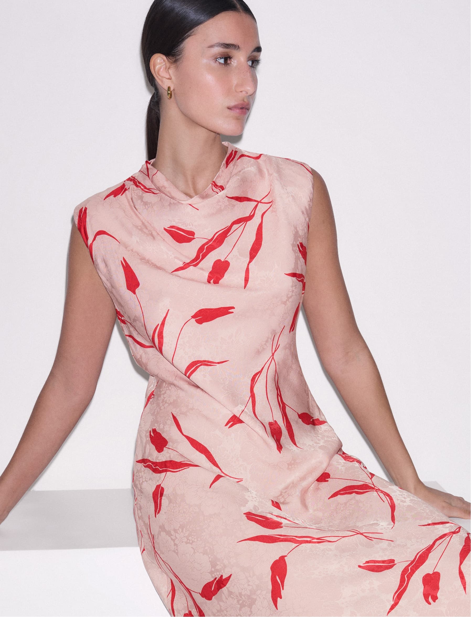 Model sat down wearing a pink dress.