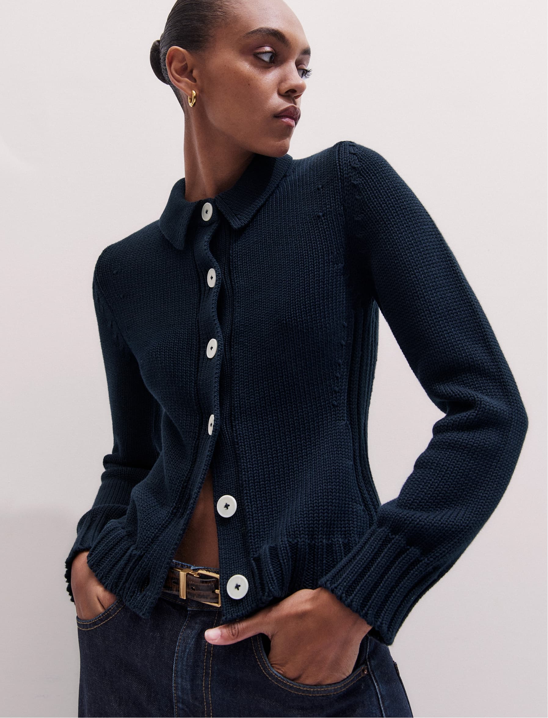 A close up shot of a woman wearing a navy cardigan and looking away from the camera.