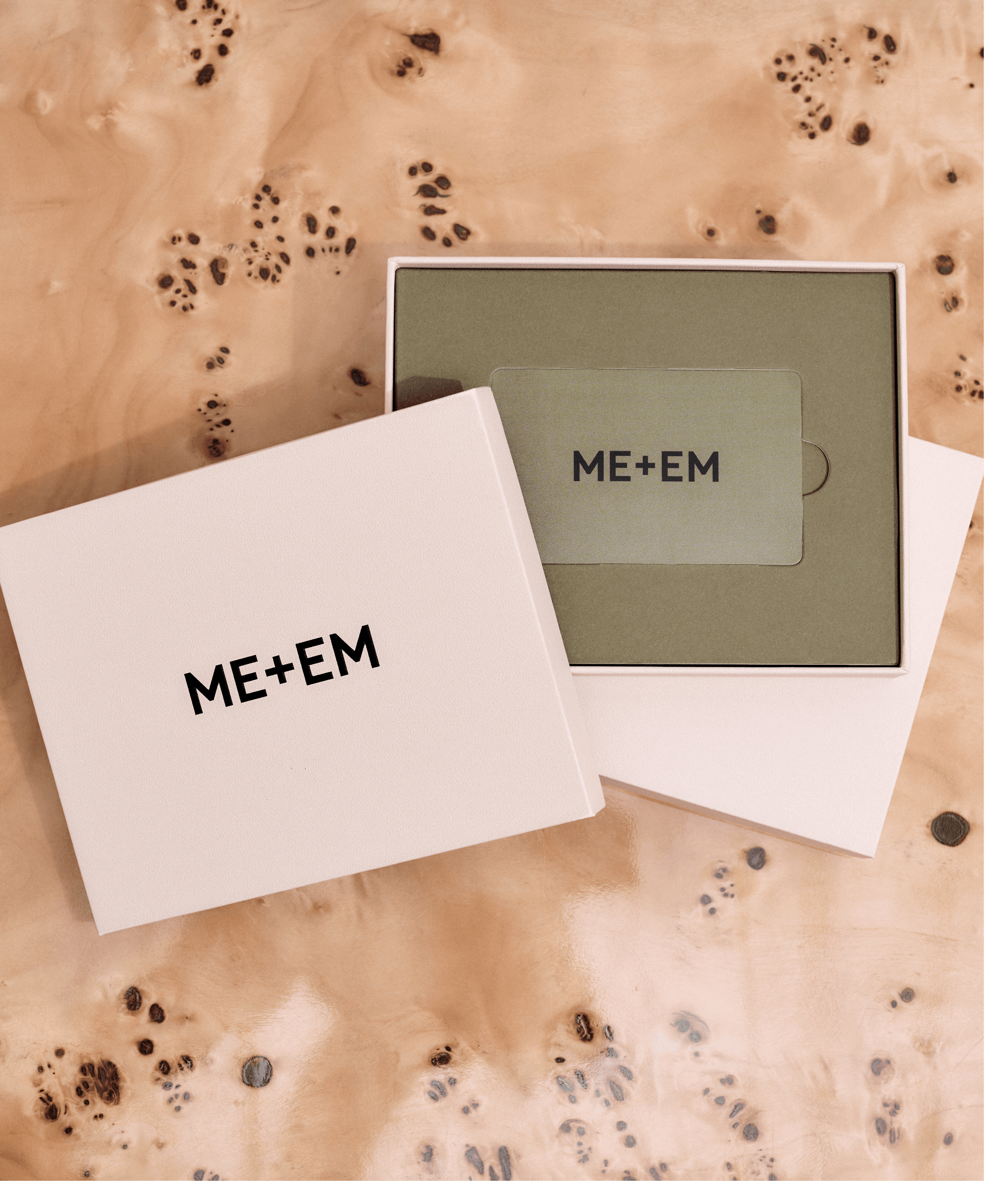 Image of ME+EM gold gift card in pink box on a wooden table