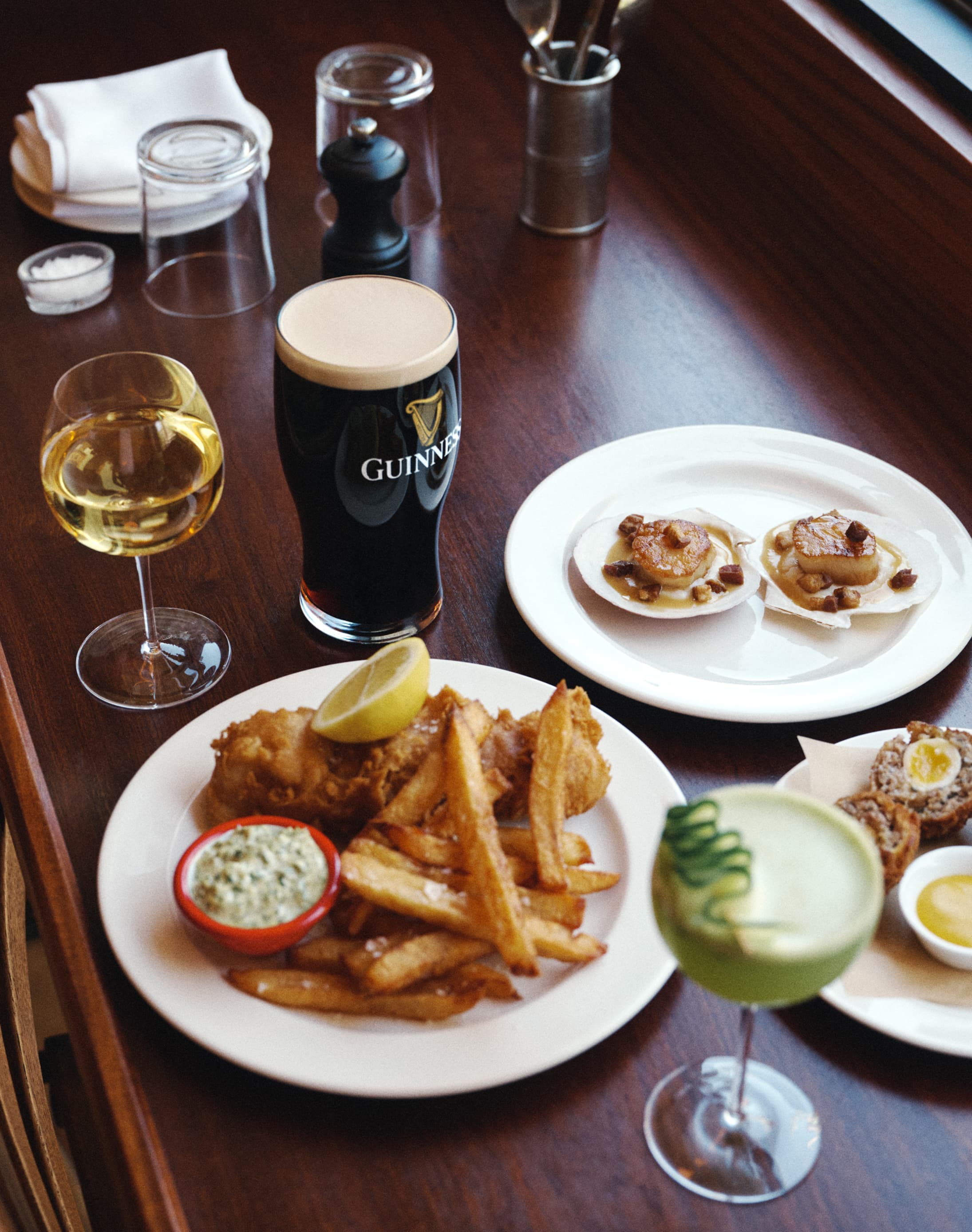 Aesthetic picture of food and drink including a pint of Guinness, a glass of wine and a plate of fish and chips.