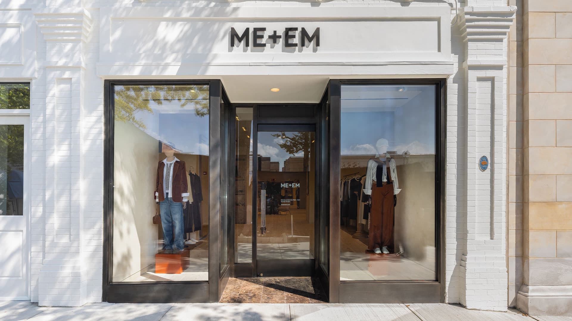 ME+EM Greenwich store outside with black trim windows and mannequins standing in windows