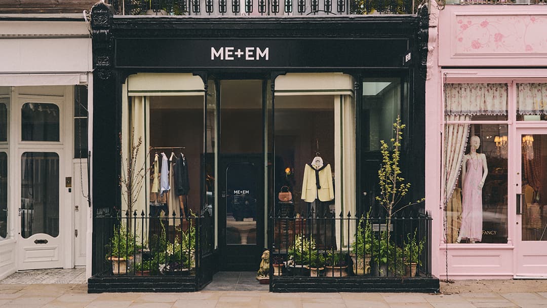 ME+EM Westbourne Grove outside store front with black gate and clothes hanging in window