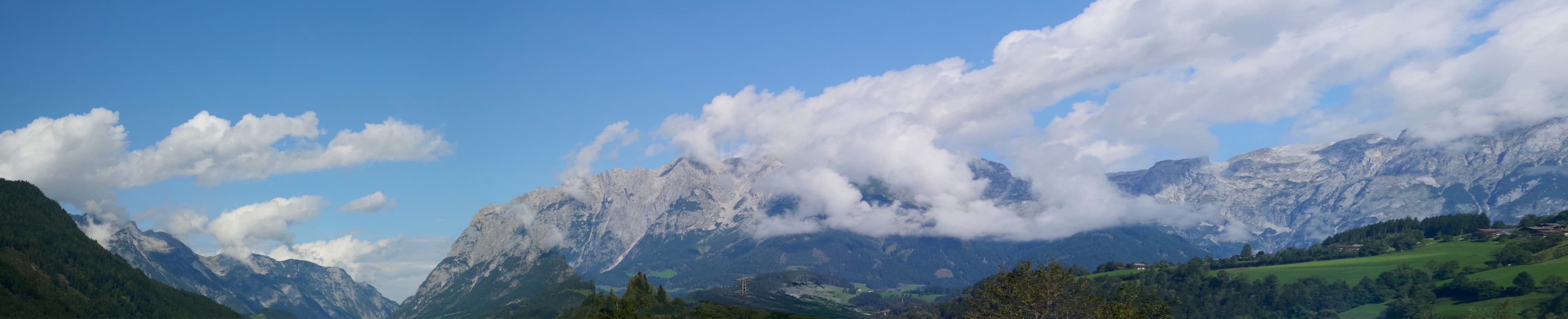 A landscape view with snow-capped mountains and clouds.