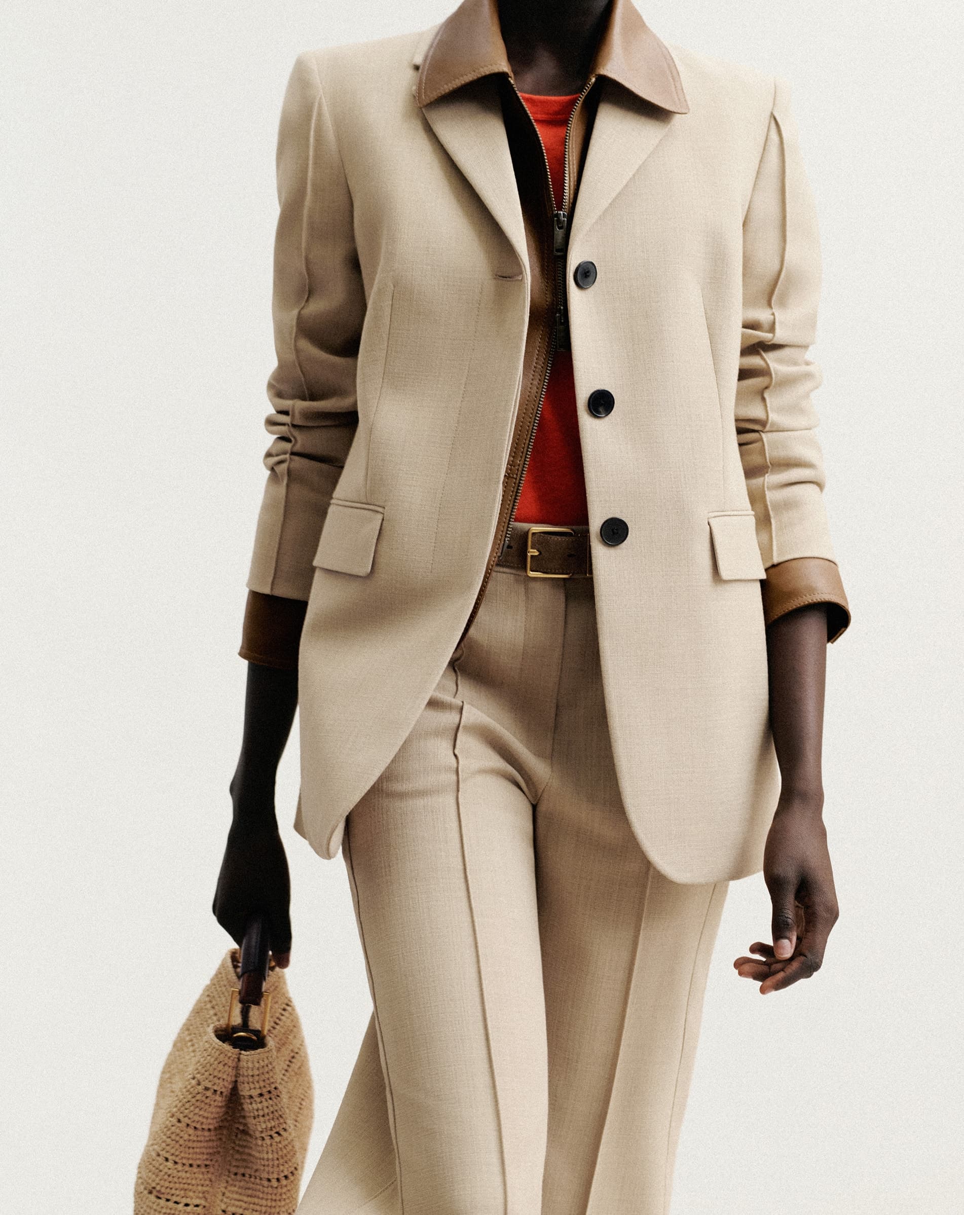 Close up shot of a woman wearing a suit and carrying a bag.