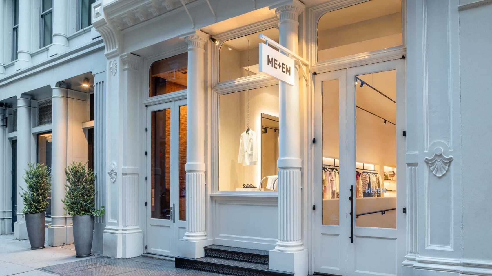 ME+EM Mercer Street store front all white with plants out front and white jacket in window