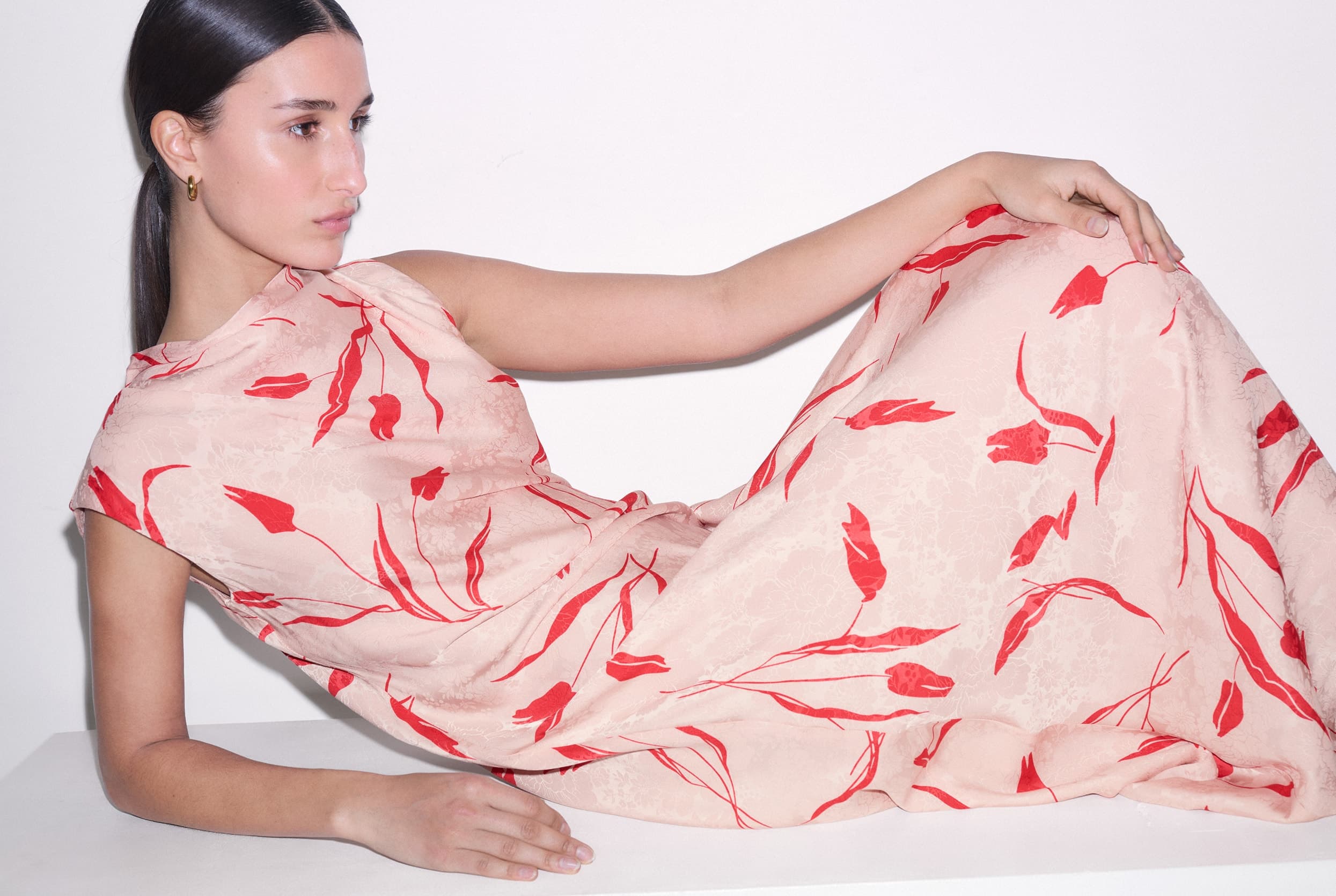 Model lying down, wearing a pink dress.