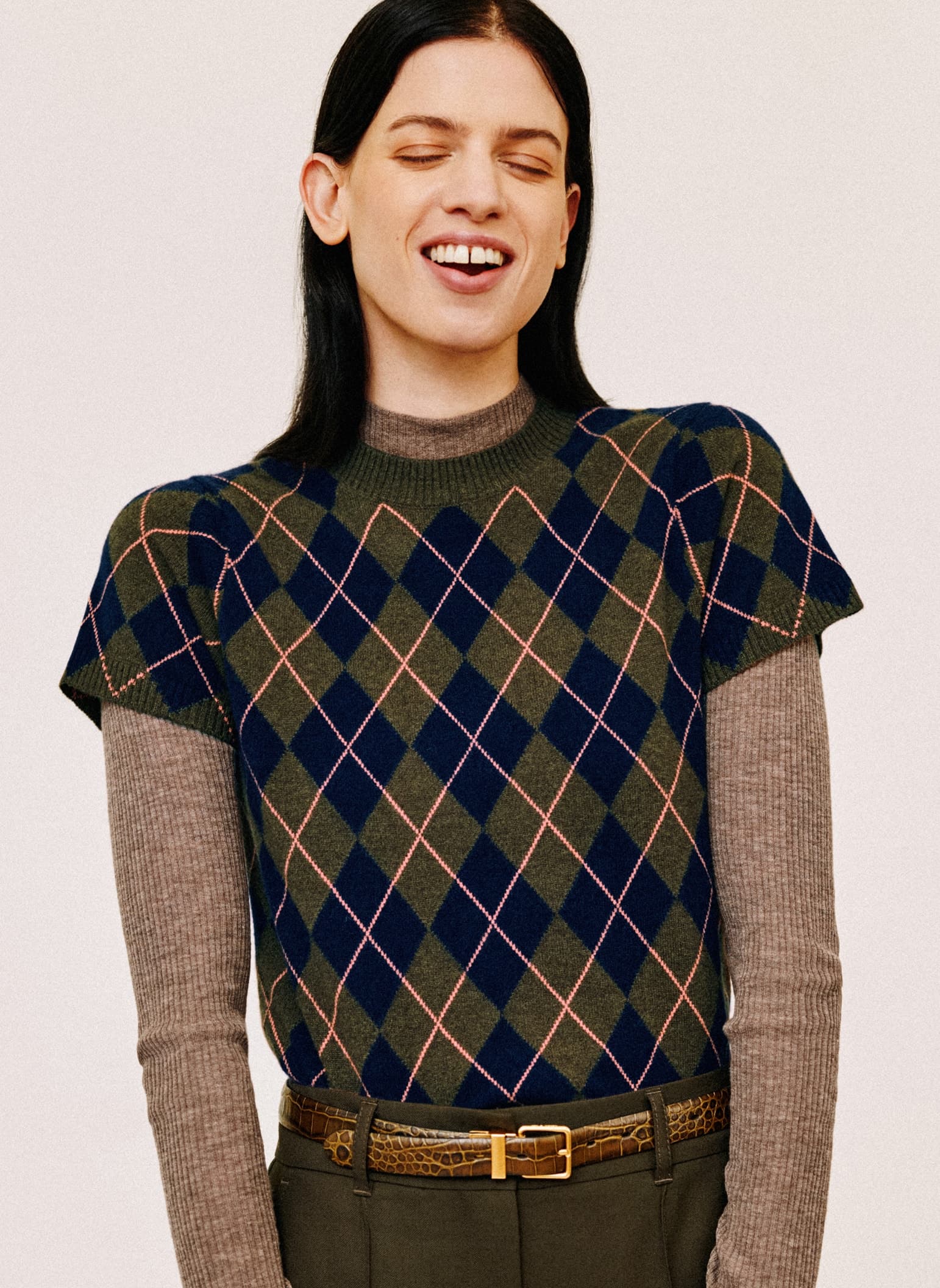 A woman smiling wearing an argyle jumper.